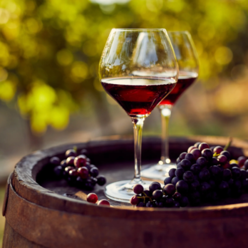 Image of wine glasses and grapes on top of a wine barrel at a winery